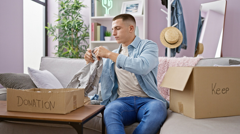 A young man sorting clothes into a donation box