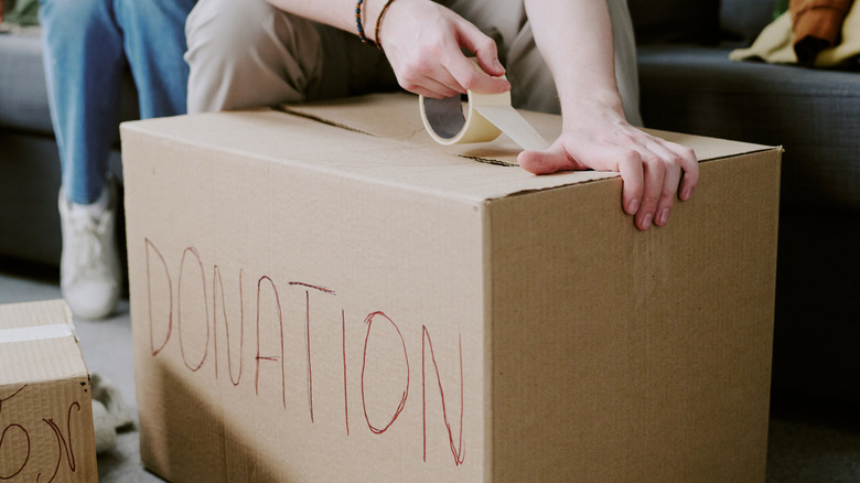 Close-up of a person taping a donations box shut