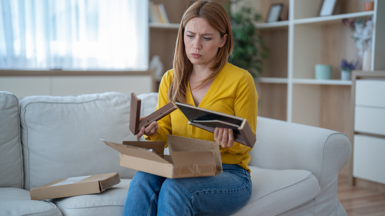 A woman sitting on a sofa looking through framed photographs