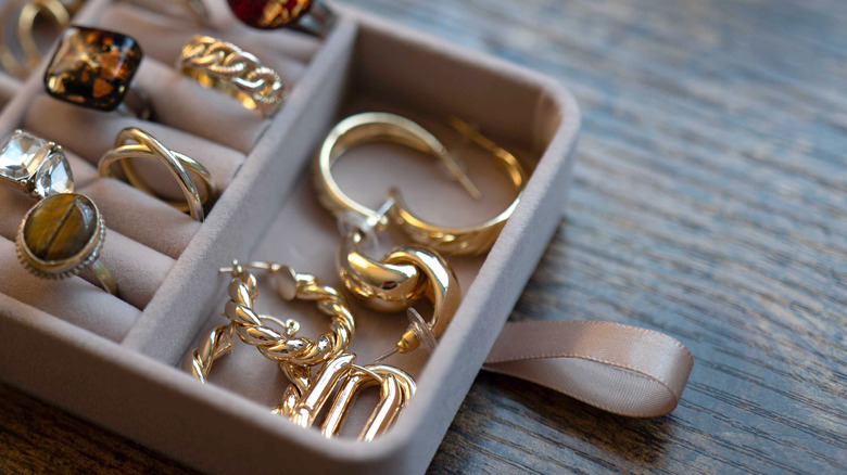 A jewelry box filled with gold rings and earrings