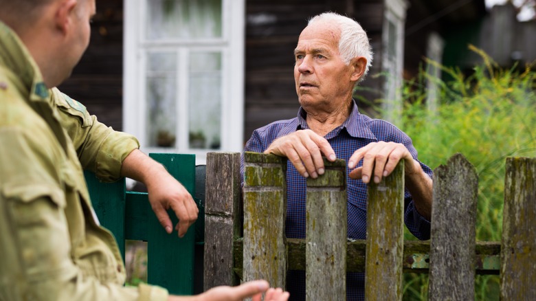 two neighbors talking over fence