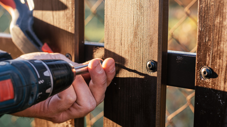person nailing fence back together