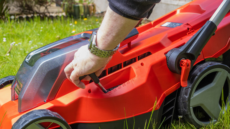 Gardener adjusting the cutting height on a lawn mower
