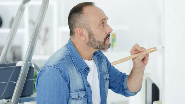Man glances up while painting