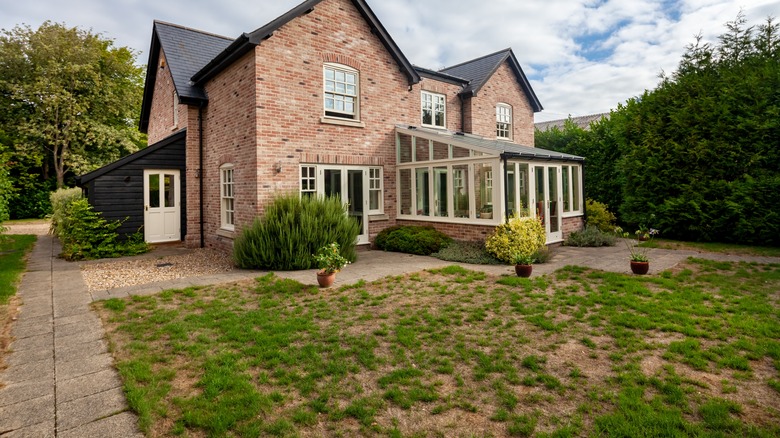 The grass in a front lawn grows patchy and has dead or bare spots.
