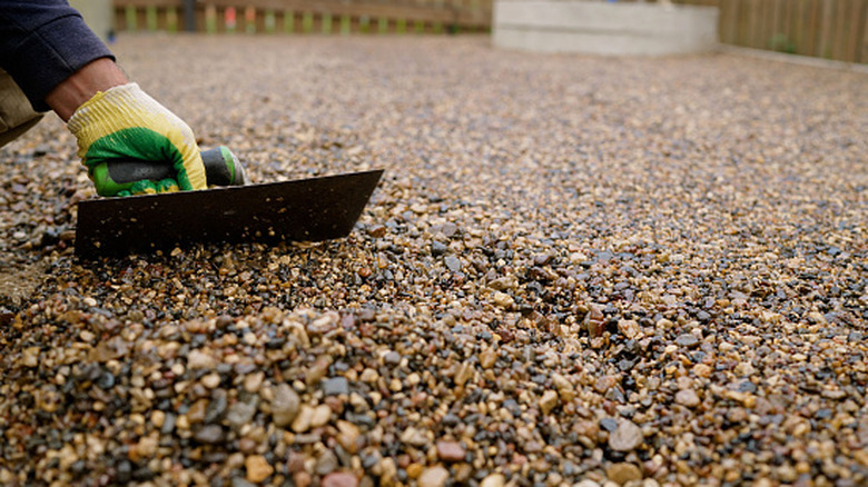 person fixing gravel driveway