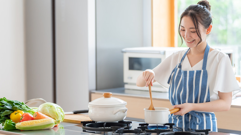 A woman cooks at a gas stove.