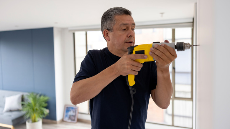man drilling hole into wall