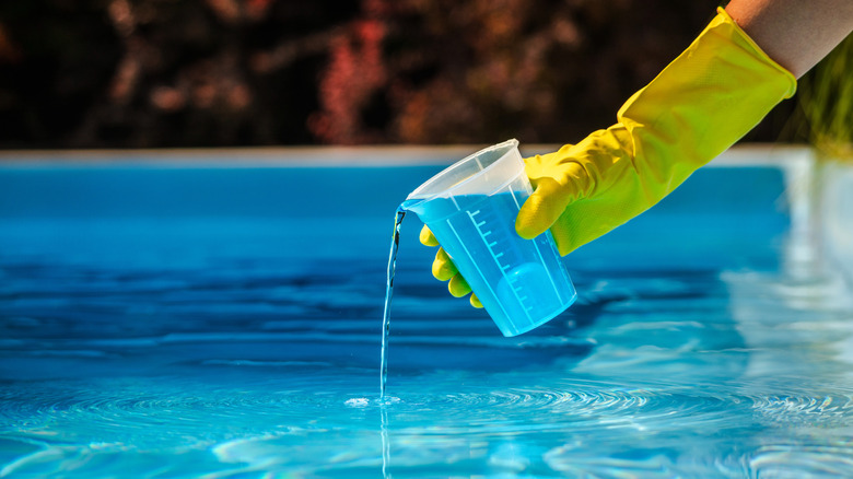 Man pouring chlorine into pool