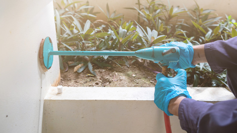 Person applying a termite treatment at a home