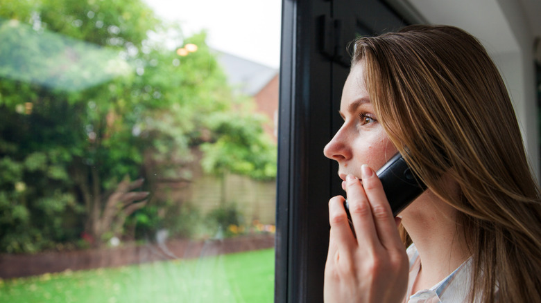 woman on phone looking out window