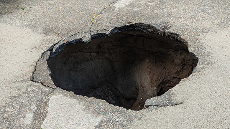 A large sinkhole is exposed on an asphalt street.