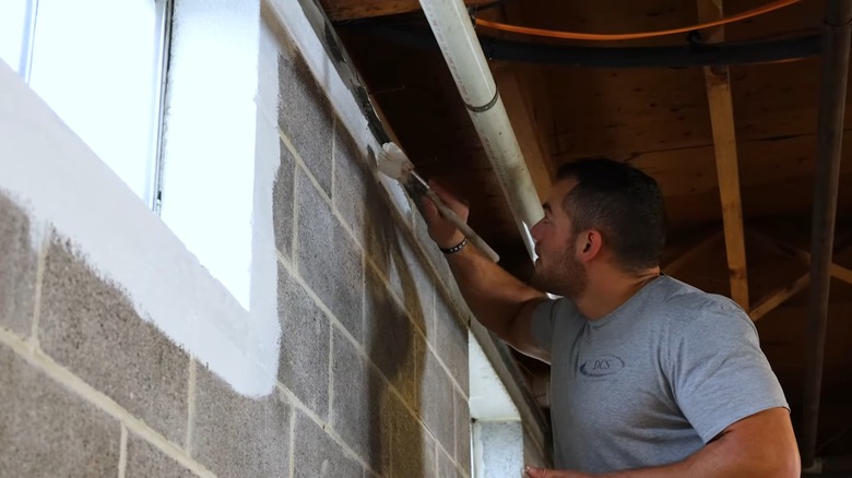 People adding sealant to a cinder block wall