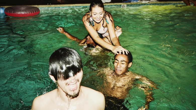 A group of young people swimming in a pool at night.