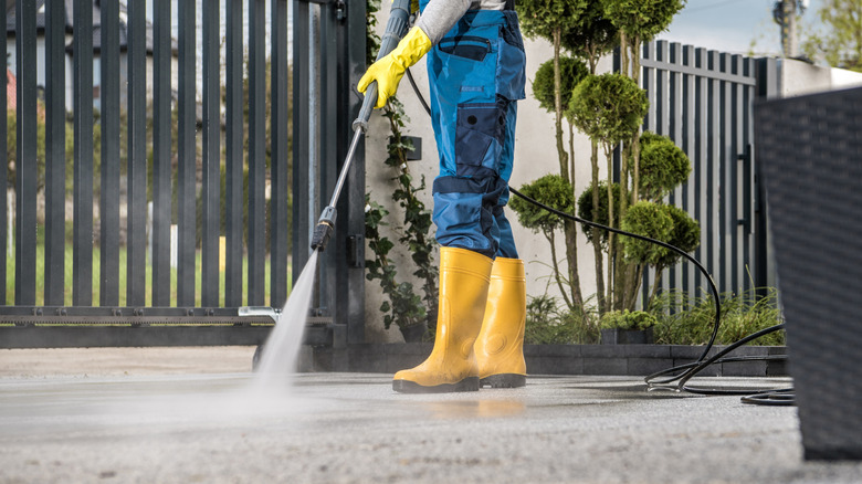 A man pressure washing his driveway tp remove utility markings