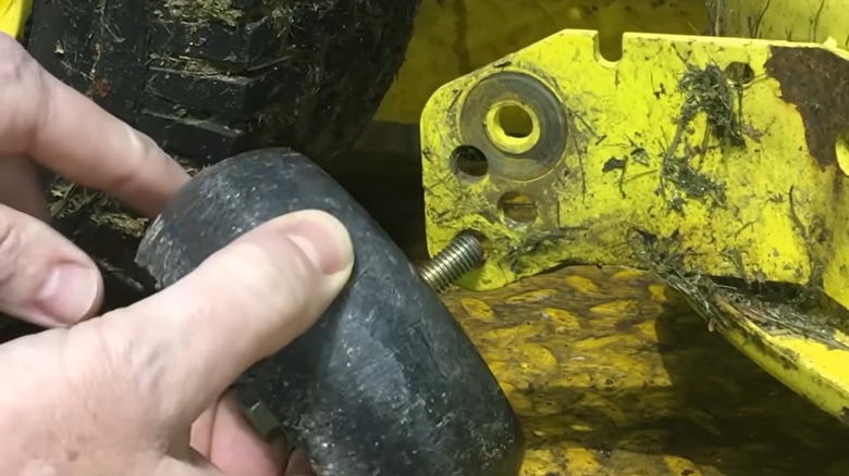 Person inserting a guide wheel into a riding mower deck