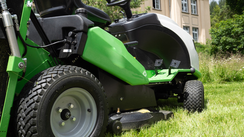 A close-up shot of a green riding lawn mower with deck wheels