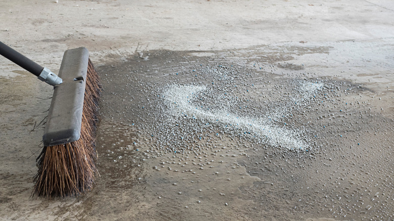 Soaking up an oil or gasoline spill with cat litter