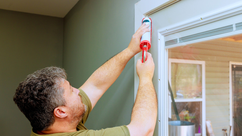 man sealing window frame