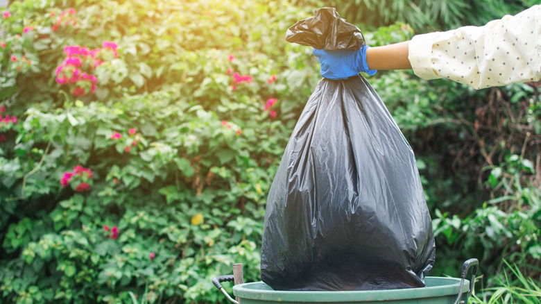 Gloved hand holding trash bag