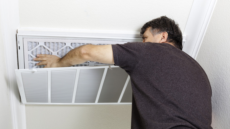 A man replacing an air filter in a vent