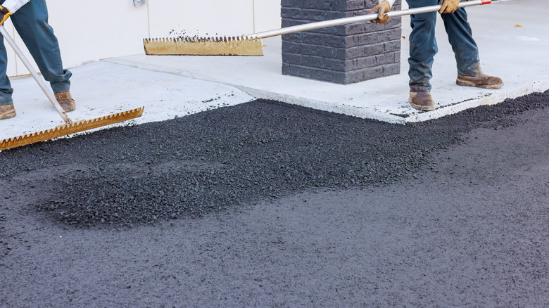 Construction workers applying new asphalt to a driveway
