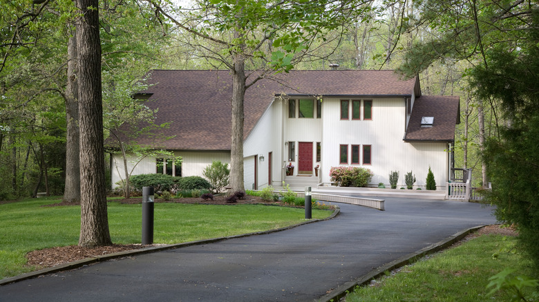 Cute white home with as asphalt driveway and trees