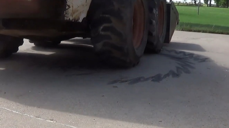 Vehicle leaving tire marks on a concrete driveway