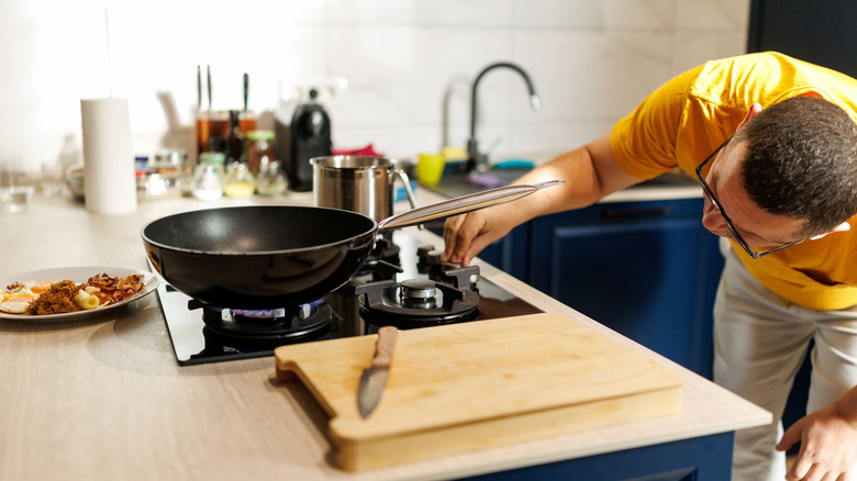 A person inspecting and adjusting the flame on a gas stove.