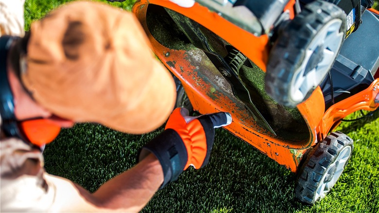 A person inspecting the blade on a mower