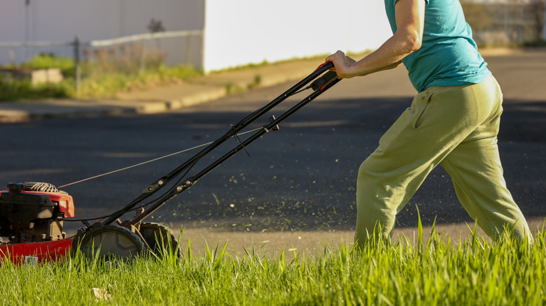 pushing lawn mower over tall grass