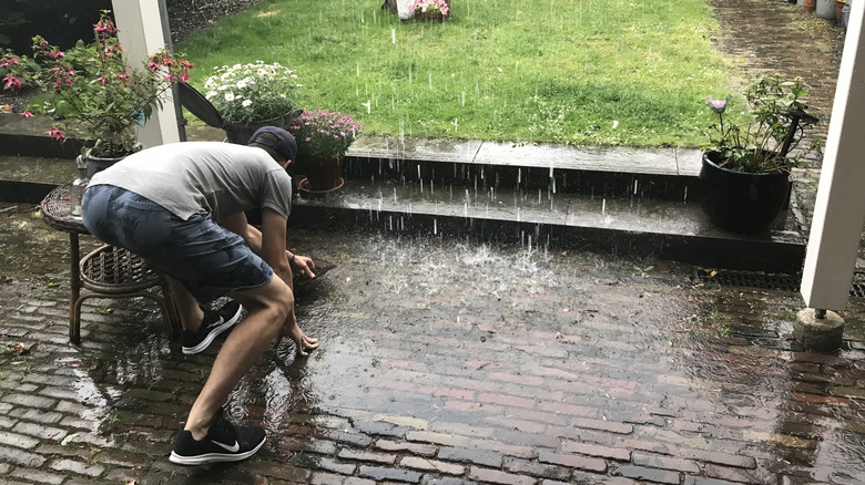 A person kneeling on their patio while it's flooding
