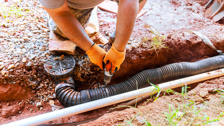 Contractor works on fixing underground pipe in yard