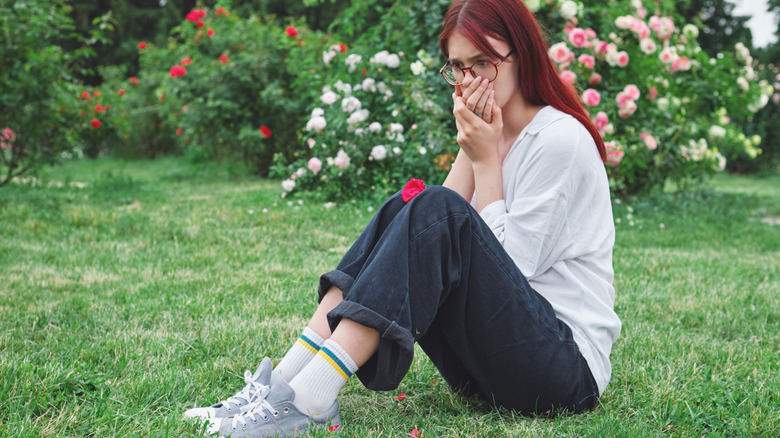 Girl with glasses reacting to bad smell in garden