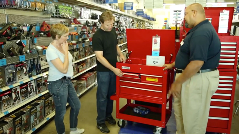 A Harbor Freight employee shows two customers a red toolbox