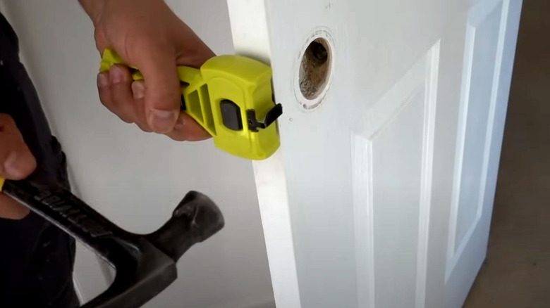 Someone using the Ryobi Latch Mortiser with a hammer to impress a latch guide into a door edge