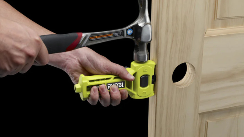 Someone using the Ryobi Latch Mortiser to chip away the excess wood on the edge of a door