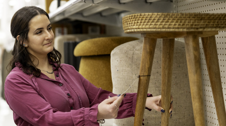 Woman checking the price tag on a stool on a shelf