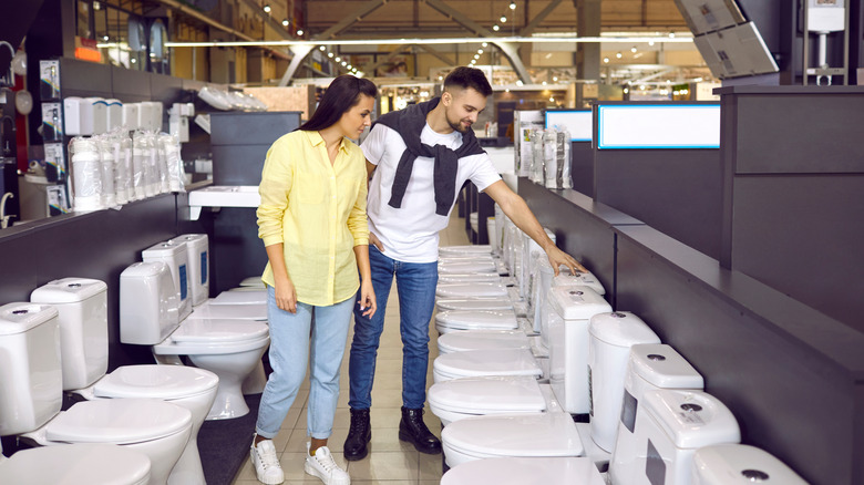 A couple looks at toilets on display in a showroom