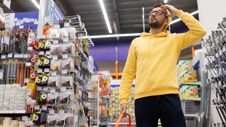 Man shopping in hardware store looking confused