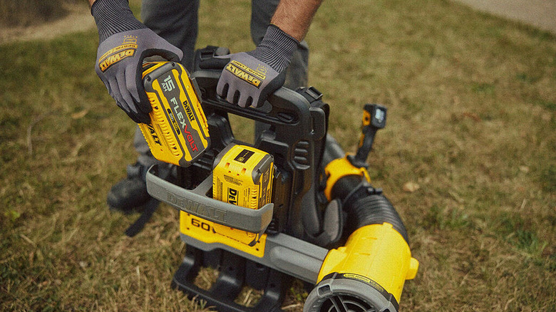 Person loading batteries into a DeWalt backpack leaf blower
