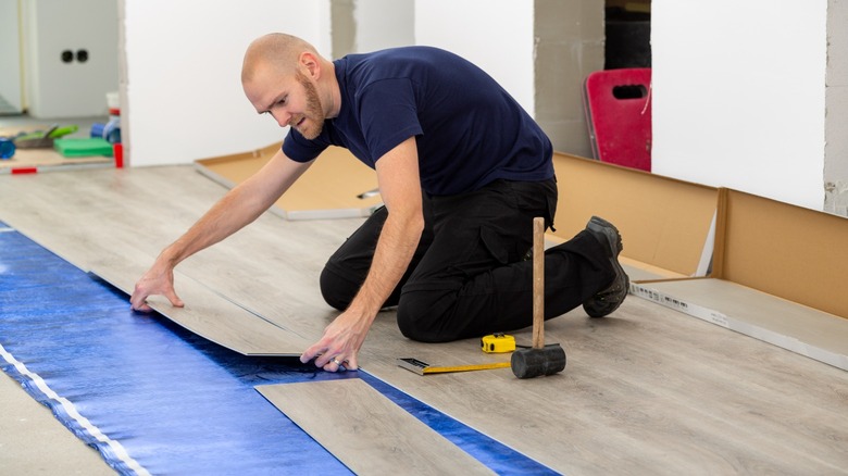 Man laying floor acoustic underlayment 