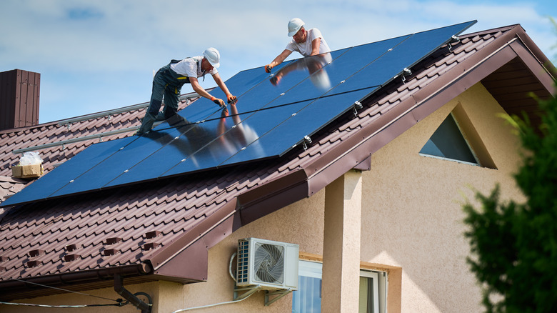 Men installing solar panels on a house.