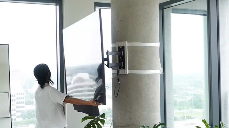 Woman turning pillar-mounted big-screen TV on full-motion mount