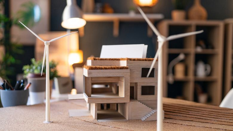 A model of a modern home near two wind turbines