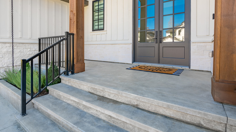 House with grey front doors, and concrete steps leading down from the porch