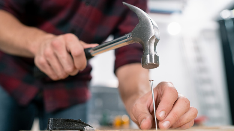 man hammering nail into wood