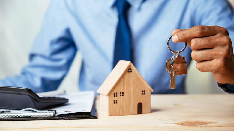 person holding keys with house