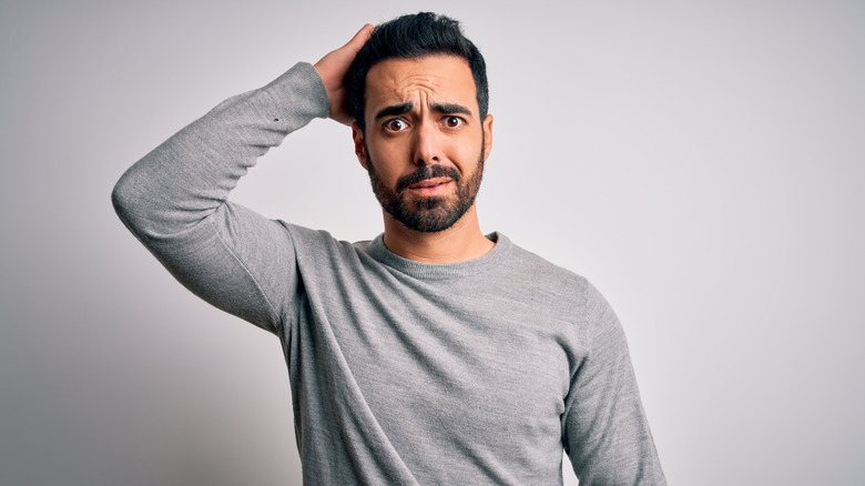 confused young man scratching head