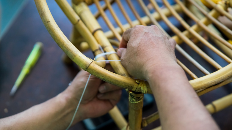 A person inspects or works on restoring a rattan chair